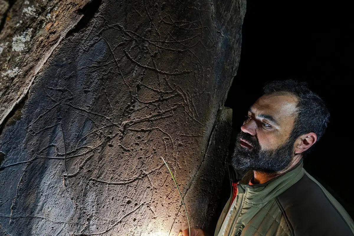 Marco Ferraz showing rock art engravings by lantern light